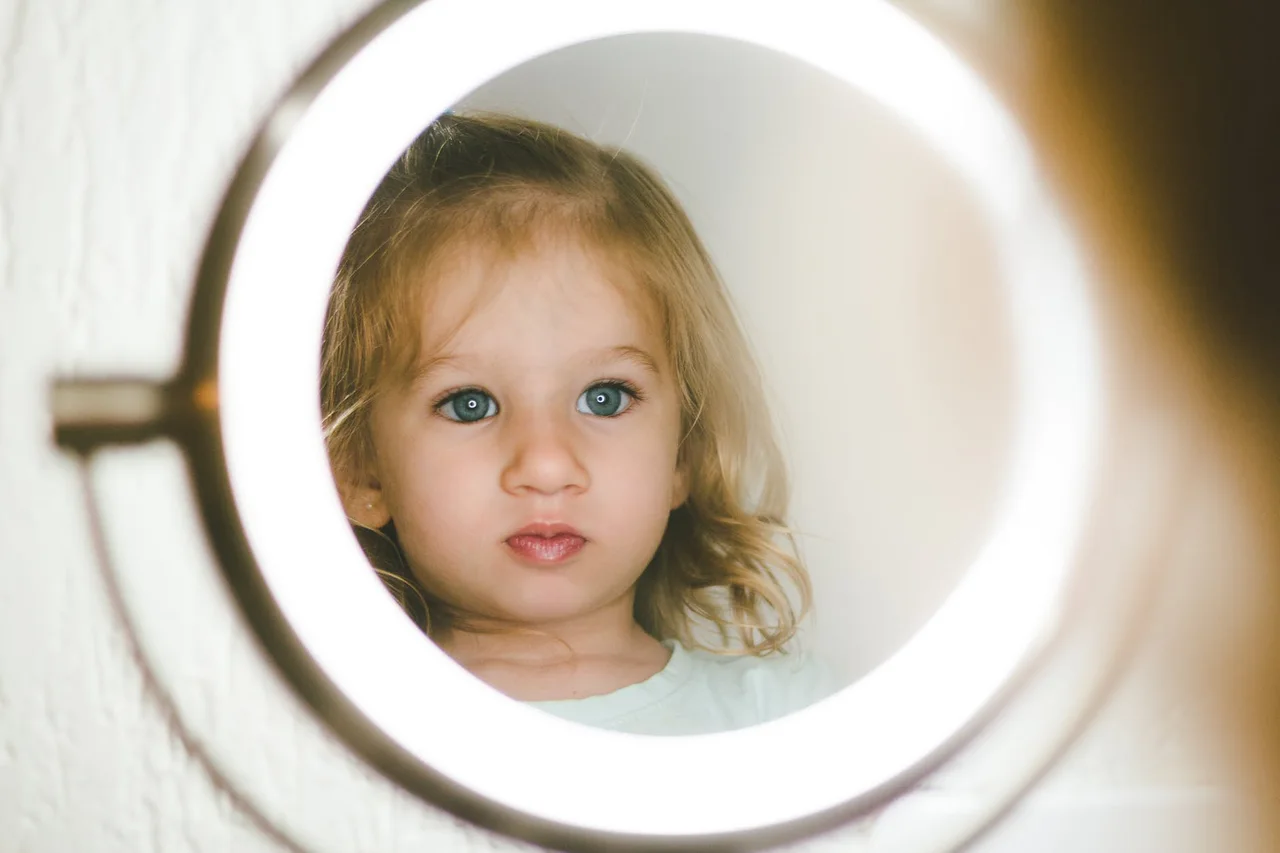 selective focus photography of girl facing lighted magnifying lamp